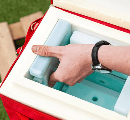 Мужчина в часах достает хладоэлементы из термоконтейнеров Biocard для перевозки с соблюдением температурного режима