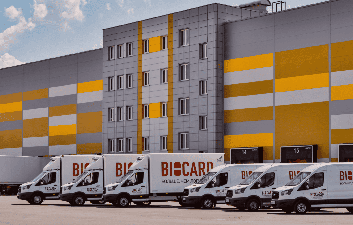 Автомобили и грузовики Biocard на парковке около склада. Biocard - перевозки грузов с температурным режимом по РФ и миру